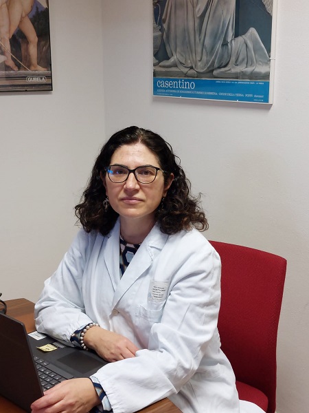 Nella foto la dottoressa Ilaria Spaghetti, con il camice seduta alla scrivania