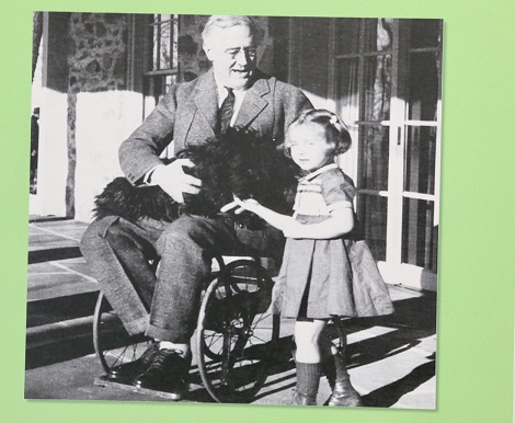 Foto in bianco e nero che ritrae un uomo su una sedia rotella con accanto, in piedi, una bambina