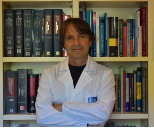 Nella foto il dottor Alessandro Capitanini, in piedi davanti a una libreria, con il camice